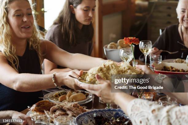 women passing food while sitting at dining table during thanksgiving - thanksgiving food stockfoto's en -beelden