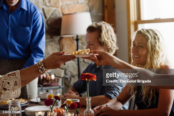 women passing plate of dessert in dining room during thanksgiving - thanksgiving indulgence stock pictures, royalty-free photos & images