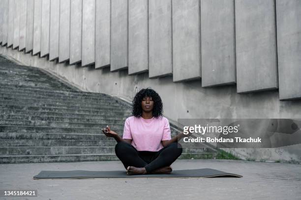 young afro american woman enjoys yoga in lotus position - yoga rug stock pictures, royalty-free photos & images