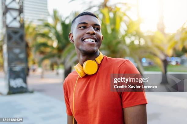 happy man with headphones standing in the street while looking away - studente universitario foto e immagini stock