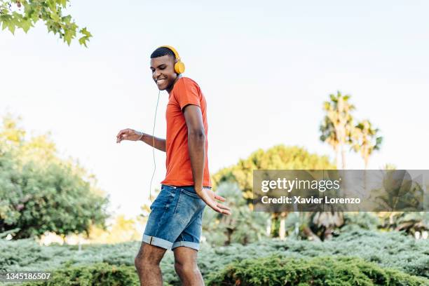 young brazilian man singing and dancing while listening music with headphones and mobile phone - guy dancing music dynamic stock pictures, royalty-free photos & images