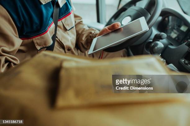 delivery man driving his van and delivering shipments. he is checking order on digital tablet - delivery driver stockfoto's en -beelden