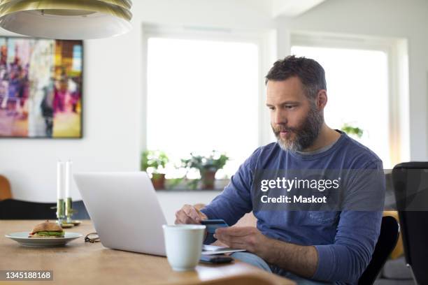 businessman paying through credit card on laptop at home - online shop stockfoto's en -beelden