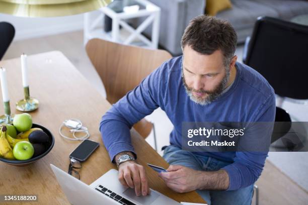 high angle view of businessman doing online payment through credit card in living room - apple credit card stock pictures, royalty-free photos & images