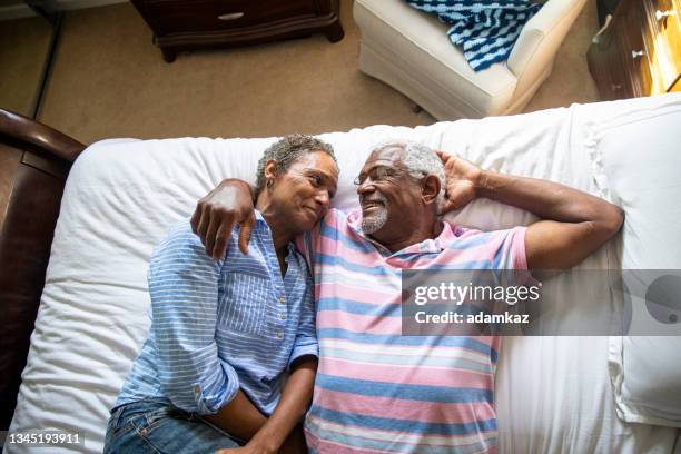 casal negro aposentado deitado na cama - black man sleeping in bed - fotografias e filmes do acervo