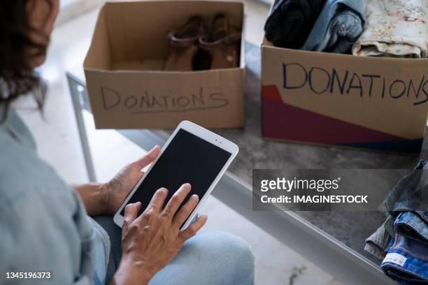 woman preparing a donation box of clothes for charity - charity benefit photos et images de collection