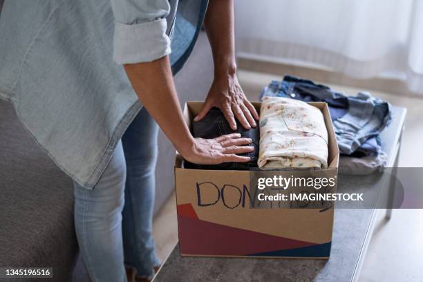 woman preparing boxes of clothes for the donation to charity - donation box stock pictures, royalty-free photos & images