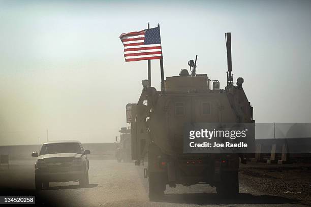Army armored vehicle flies an American flag as it provides security escort for a convoy of vehicles pulling equipment that is heading to Kuwait from...