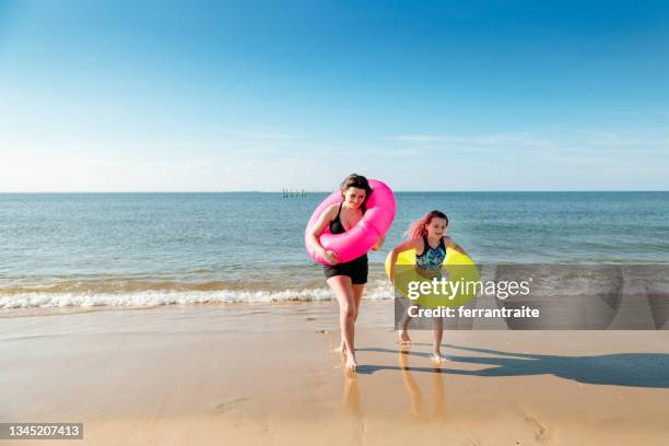 sisters swimming with inflatable rings on the sea - virginia beach stock pictures, royalty-free photos & images