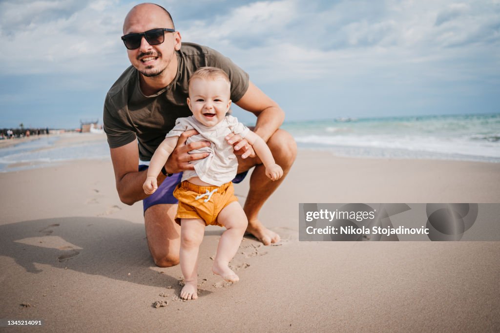 The father teaches the son the first steps on the beach