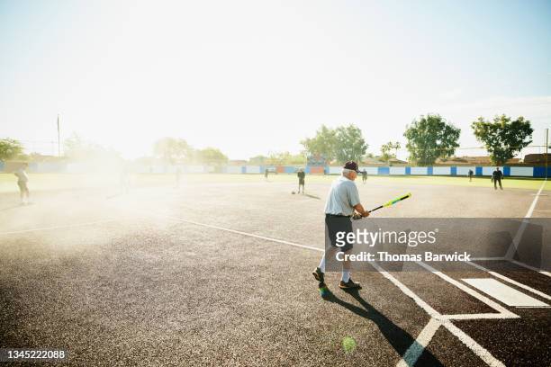 Wide shot of senior softball player preparing to bat during game on summer morning