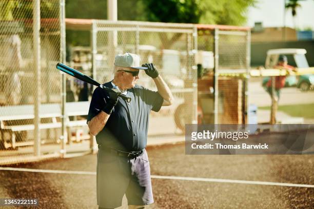Medium wide shot of senior softball player preparing for at bat during game on summer morning
