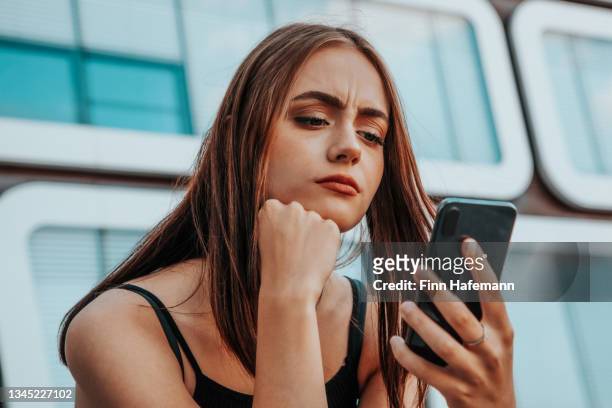worried woman checking messages on smart phone - cell phone confused stockfoto's en -beelden