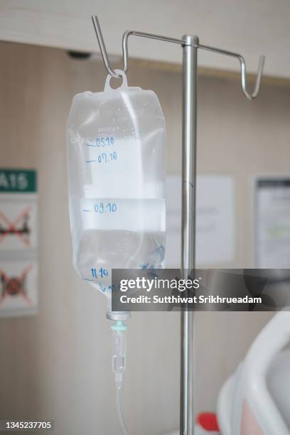 close-up of iv drip hanging against wall in hospital - drip bag stockfoto's en -beelden