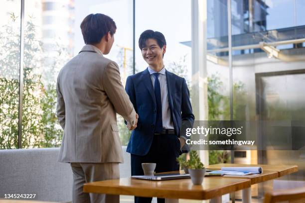 two asian business men are shaking hands - asian shaking hands stockfoto's en -beelden