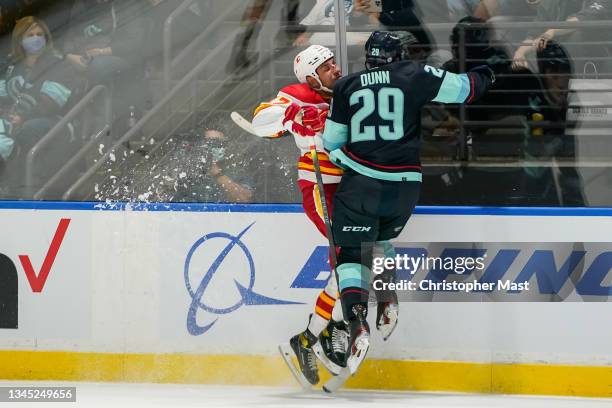 Vince Dunn of the Seattle Kraken collides with Milan Lucic of the Calgary Flames along the wall during the first period of a game between the Calgary...
