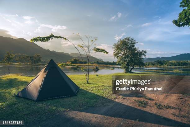 tent at sunrise on green grassland with mountain background. morning time with camping and fresh air after passing lockdown covid19 - camping fotografías e imágenes de stock