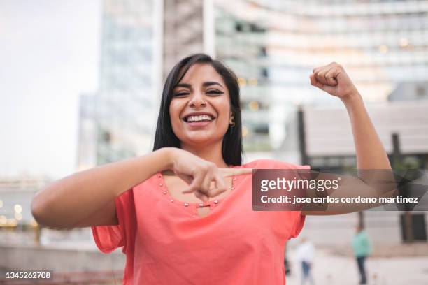empowered latin woman showing her strong arm - showing skin stock pictures, royalty-free photos & images