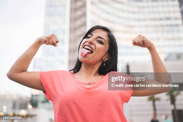 pretty woman with raised arms showing muscle, women's day - proud fotografías e imágenes de stock