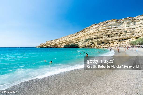 bathers swimming in the crystal sea, matala beach, crete - crete scenics stock pictures, royalty-free photos & images