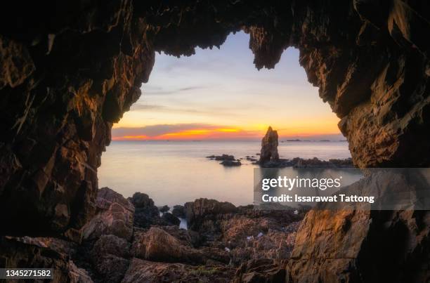 fisherman standing in front of a cave entrance at sunset - luce alla fine del tunnel foto e immagini stock