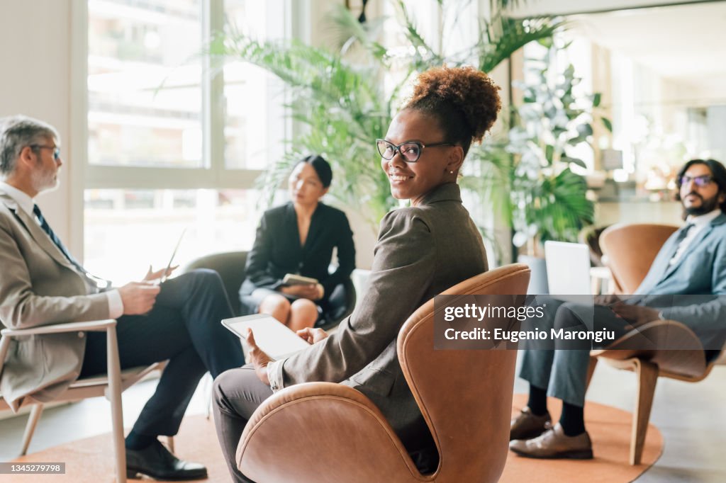 Italy, Portrait of businesswoman with tablet at meeting in creative studio