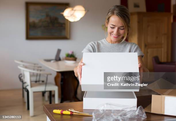 happy woman opening parcel at home - receiving fotografías e imágenes de stock