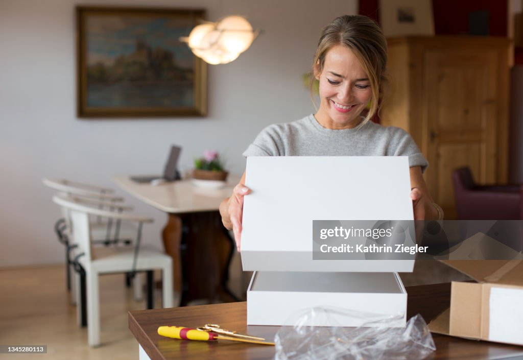 Happy woman opening parcel at home