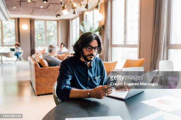 italy, man working at table in creative studio - incidental people stock pictures, royalty-free photos & images