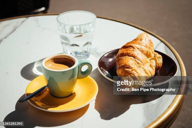 france, paris, croissant, coffee and glass of water on sidewalk cafe table - french cafe bildbanksfoton och bilder