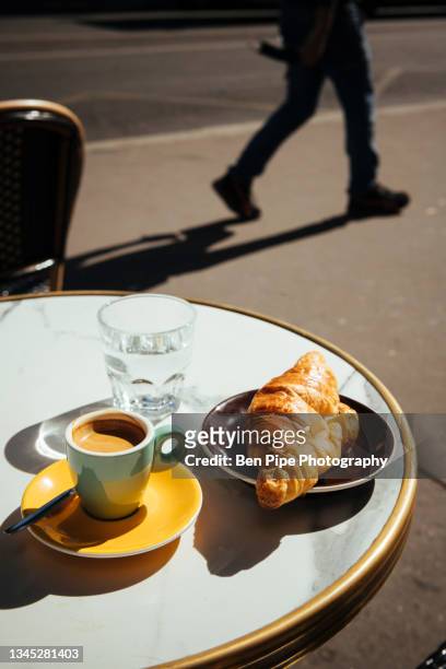 france, paris, croissant, coffee and glass of water on sidewalk cafe table - paris france stock-fotos und bilder