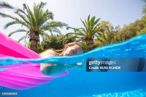 spain, mallorca, woman floating on water in swimming in pool - pool raft imagens e fotografias de stock