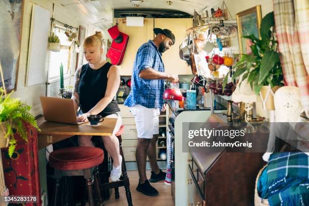 couple in 30s and 40s keeping busy in narrowboat cabin - houseboat stock pictures, royalty-free photos & images