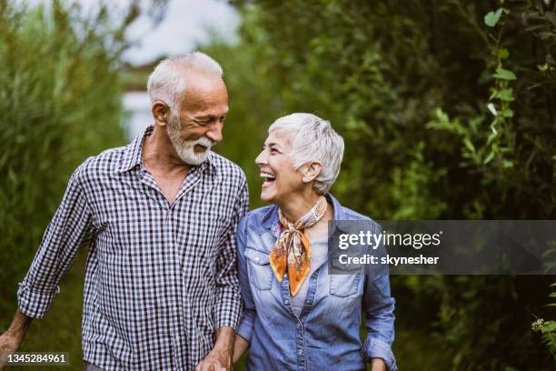 happy mature couple communicating while walking in nature. - older couple stockfoto's en -beelden