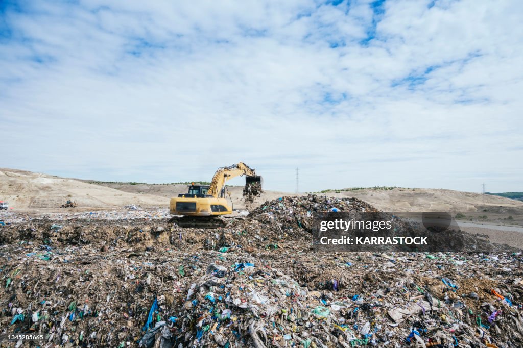 Excavator sorting metals for recycling at a recycling center