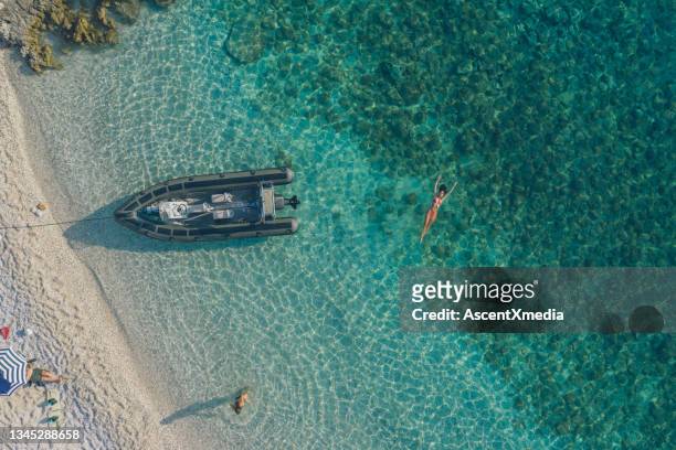 aerial view of young woman floating in blue waters - aerial beach view sunbathers stock pictures, royalty-free photos & images