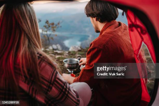 rear view of a campers cooking soup - camping stove stockfoto's en -beelden