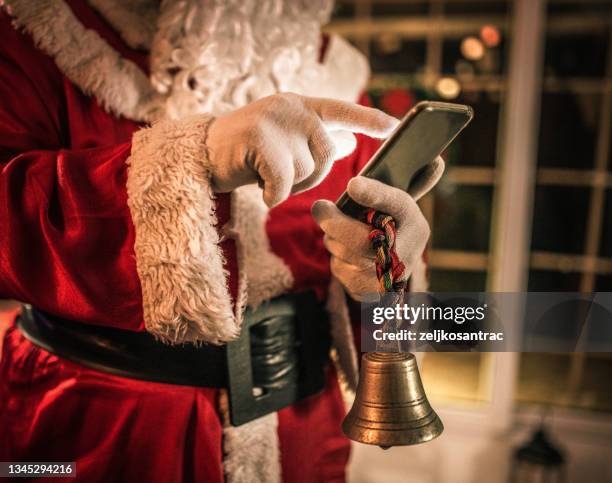 feliz viejo santa claus usando computadora portátil y teléfono en casa - the real santa claus fotografías e imágenes de stock
