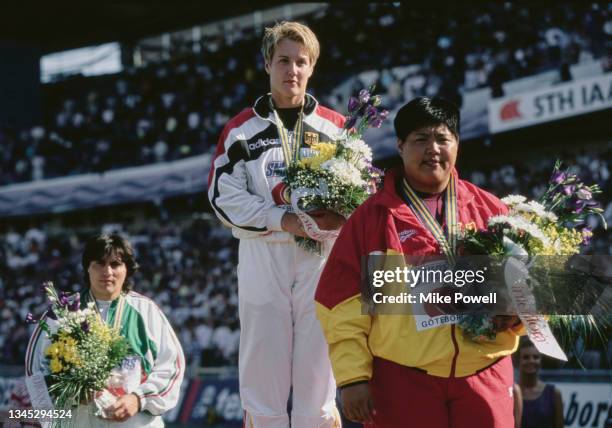 Gold medalist Astrid Kumbernuss of Germany stands on the victory podium with silver medalist Huang Zhihong of China and bronze medalist Svetla...