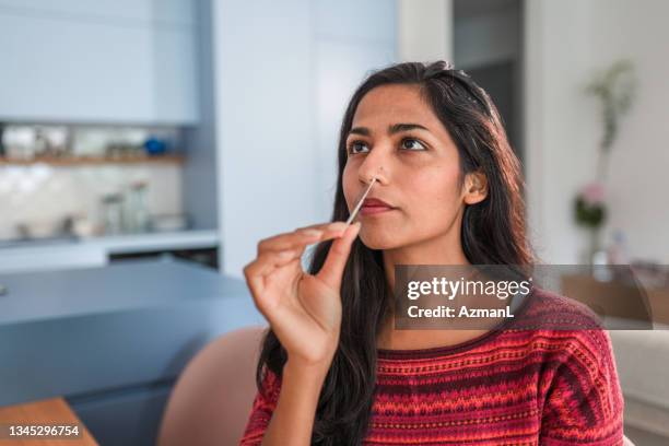 gros plan d’une jeune femme indienne en train de passer un autotest covid dans la cuisine - screening photos et images de collection