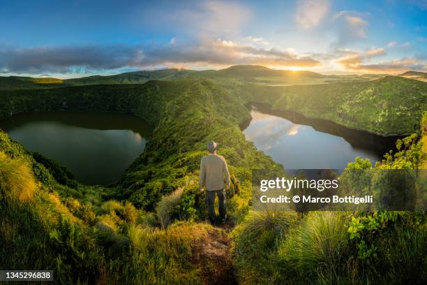 man enjoying the sunrise from the top of a caldera - flores stock pictures, royalty-free photos & images