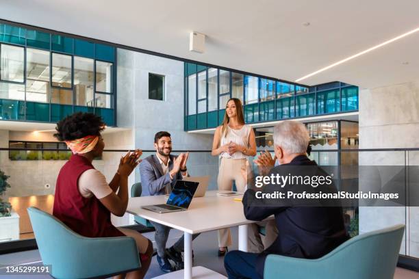 modern female manager is working on improvement of business results while spending time in a company hallway with a multi-ethnic group of her colleagues. - business milestones stock pictures, royalty-free photos & images