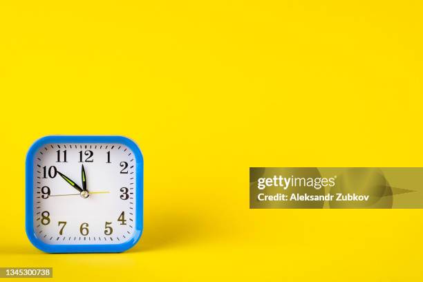 a small plastic alarm clock in retro style on a bright yellow background. the concept of the speed and rapidity of time and the flow of life. copy space. - wind up toy foto e immagini stock