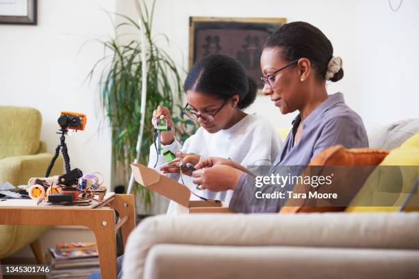 mother and daughter looking at coding materials in living room - femalefocuscollection stock-fotos und bilder