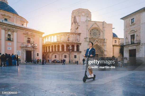 woman riding motor scooter at plaza de la virgen in valencia - kathedraal stockfoto's en -beelden