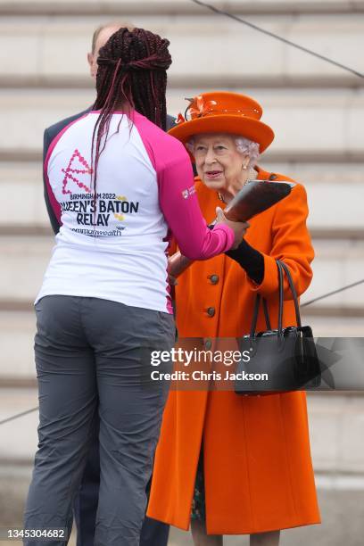 Queen Elizabeth II passes the Baton to first Batonbearer, Kadeena Cox during the launch of The Queen's Baton Relay for Birmingham 2022, the XXII...