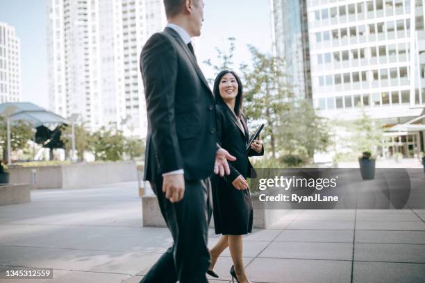 colegas de negocios discuten el trabajo mientras caminan hacia la oficina - bellevue washington state fotografías e imágenes de stock