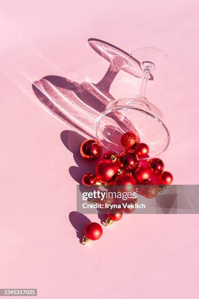 cocktail glass and christmas decoration red balls on pastel pink background. - christmas still life fotografías e imágenes de stock