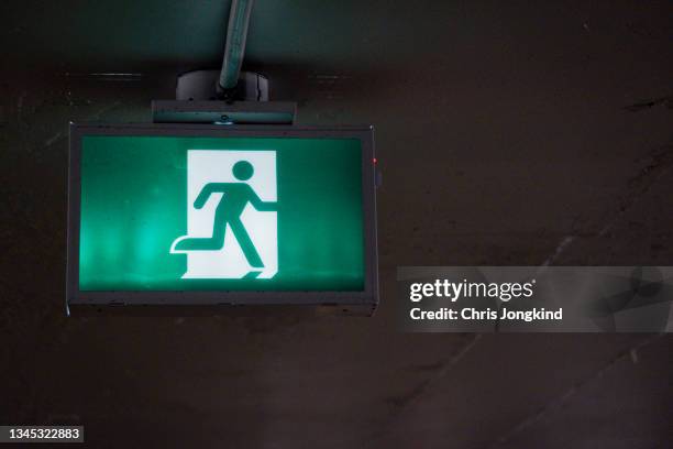 green emergency exit sign hanging from ceiling - fire exit sign stock pictures, royalty-free photos & images