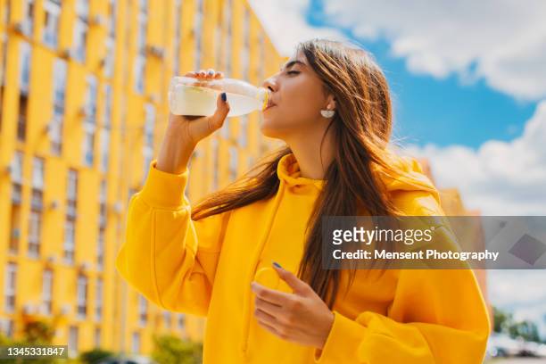 woman drinking juice against yellow buildings - colorful fruit ストックフォトと画像